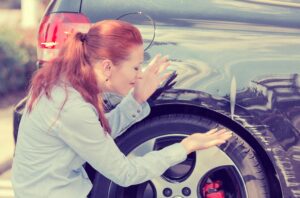 woman inspecting hit-and-run damage